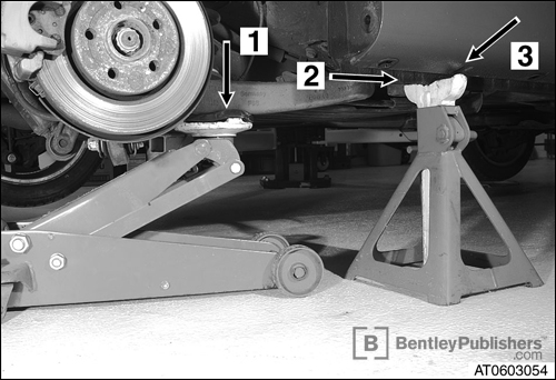 Proper positioning of floor jack and jack stand to safely lift vehicle. (BentleyPublishers.com watermark not printed on actual product.)